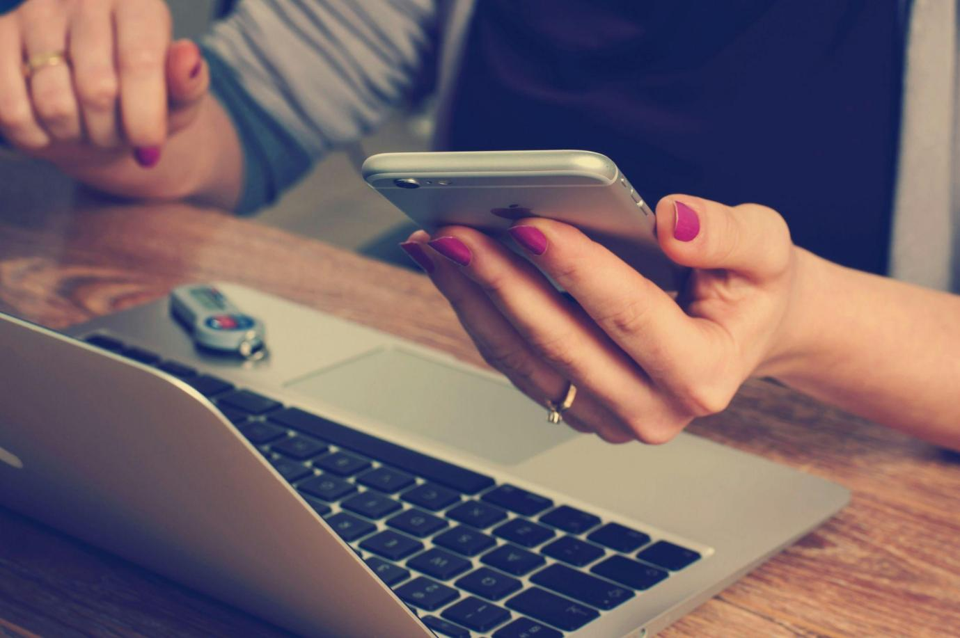 person in front of a laptop holding a phone